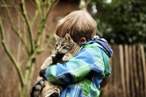 Boy hugging a cat.